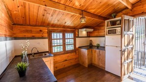 Eine Holzhütte-ähnliche Küche mit Fenster, Spüle, Schränken und einem Kühlschrank.