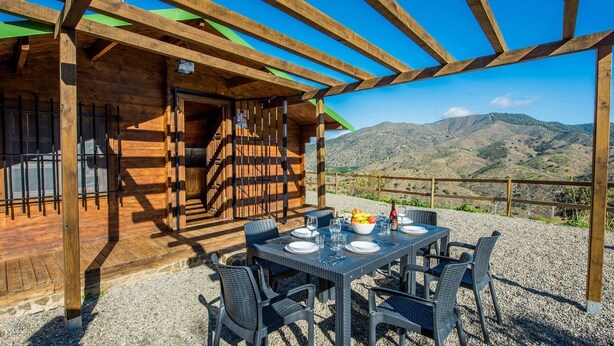 Eine Holzterrasse im Freien mit Esstisch, mit Blick auf eine Berglandschaft.