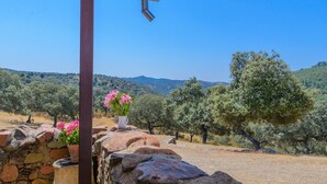 A stone wall with a white vase of pink flowers and a metal structure. - El Cortijo de Camama Villaviciosa de Córdoba by Ruralidays (Córdoba)