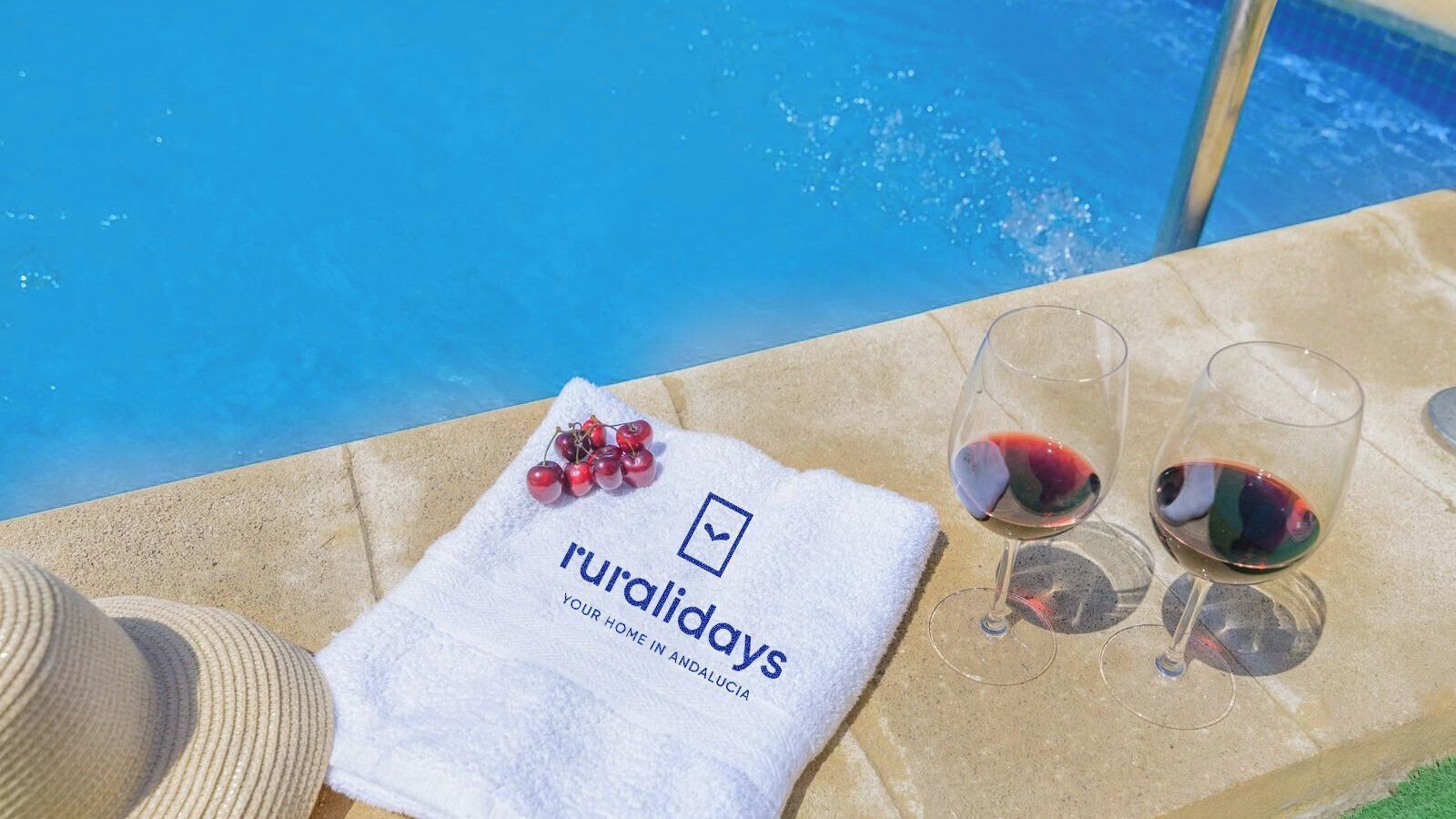 A poolside setting with a towel, grapes, and wine glasses.