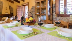 A dining table set with white plates, green placemats, and wine glasses, with a fruit basket in the center. - El Cortijo de Camama Villaviciosa de Córdoba by Ruralidays (Córdoba)