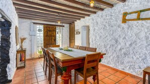 Un comedor rústico con una mesa y sillas de madera, piso de baldosas y pared de piedra.