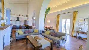 A spacious living area with a sofa set, a wooden coffee table, and a kitchen in the background. - Finca Las Encinillas Arcos de la Frontera by Ruralidays (Cádiz)