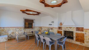 A dining area with a stone wall, a fireplace, and a tiled floor. - Torreón de Morayma Baena by Ruralidays (Córdoba)