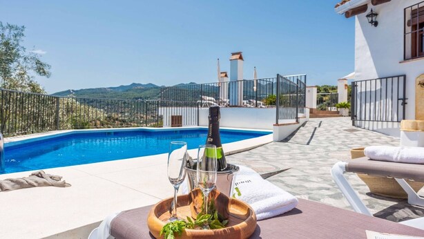 A poolside setting with a bottle of champagne, glasses, and a tray of food. - Guajar 2 Monda by Ruralidays (Málaga)