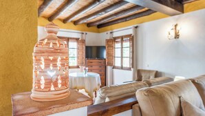 A rustic interior with a wooden table, a large vase, a sofa, and a kitchen in the background. - Guajar 2 Monda by Ruralidays (Málaga)