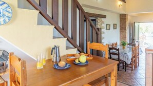 Una mesa de madera para comer con alimentos para el desayuno, una cafetera y vasos de jugo de naranja.