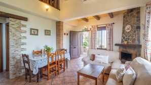 Un comedor con una mesa y sillas, un sofá, una chimenea y una pared de piedra.