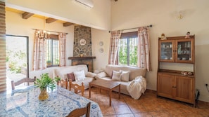 Una sala de estar acogedora con chimenea de piedra, un sofá, una mesita de centro y un aparador con puertas de cristal.