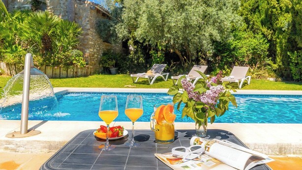 A poolside setting with a table, two glasses of orange juice, a pitcher of orange juice, a plate of strawberries, and a book. - Tomas Antequera - La Higuera by Ruralidays (Málaga)