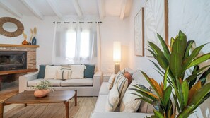 Una sala de estar con sofá, mesa de centro, chimenea y una planta.