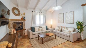 A living room with a fireplace, two sofas, a coffee table, and a large plant. - Tomas Antequera - La Higuera by Ruralidays (Málaga)