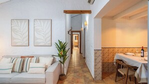 A narrow hallway with a sofa, a potted plant, and a table with a bottle and glasses. - Tomas Antequera - La Higuera by Ruralidays (Málaga)
