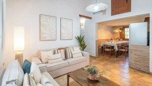 A living room with a sofa, a dining area with a table and chairs, and a kitchen with a refrigerator. - Tomas Antequera - La Higuera by Ruralidays (Málaga)