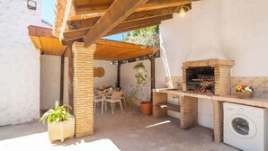 An outdoor kitchen area with a brick oven, a washing machine, and a dining table with chairs. - Tomas Antequera - La Higuera by Ruralidays (Málaga)