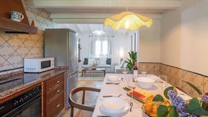 Una cocina con comedor, microondas, refrigerador, pileta y mesa lista para comer.