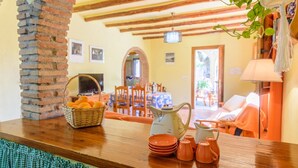 A cozy room with a wooden table, a brick wall, and a view of the outdoor seating area. - Cortijo Las Pitas Órgiva by Ruralidays (Granada)