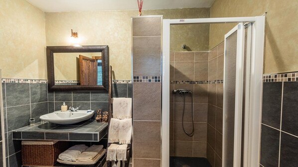 Un bagno con lavandino, specchio, portascopevoli e zona doccia.