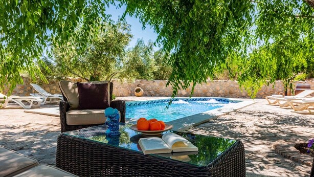 A poolside area with a wicker table, lounge chairs, and a book.