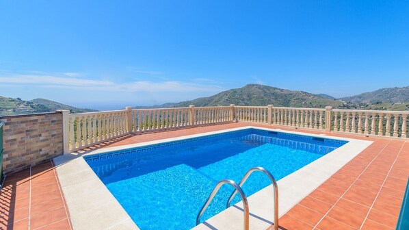 A rectangular swimming pool with a white border and a metal ladder, surrounded by a tiled deck and a white balustrade. - Cortijo Metomela Torrox by Ruralidays (Málaga)