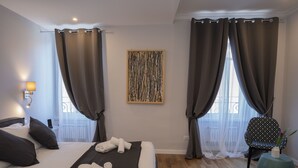 Une chambre d’hôtel avec un lit, une chaise, une table et un tableau au mur.