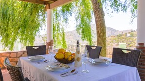 A table set for four with a basket of lemons, a bottle of olive oil, and wine glasses. - Las Esparragueras Cómpeta by Ruralidays (Málaga)