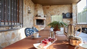 A stone-walled room with a fireplace, a dartboard, and a table set with a teapot, cups, and snacks. - Alojamiento Rural Soler Pozo Alcón by Ruralidays (Jaén)