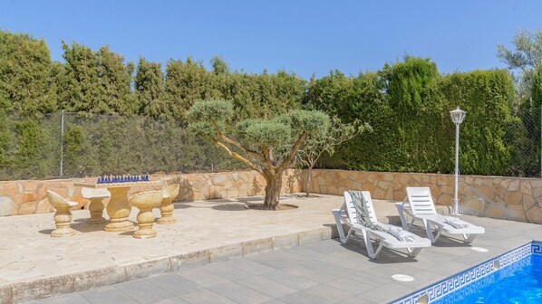 A poolside area with a stone table, lounge chairs, and a sign that reads "AMERITERRA". - Alojamiento Rural Soler Pozo Alcón by Ruralidays (Jaén)