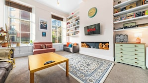 A modern living room with a sofa, a coffee table, a bookshelf, and a fireplace. - Vibrant Spacious Apartment In West End (Glasgow)