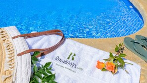 Ein Handtuch mit einer Webadresse, ein Paar Flip-Flops und eine Rose am Pool.