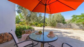 An outdoor patio with a round glass table, two chairs, and a large orange umbrella. - Cuevas La Chumbera - Cerezos 2pax Fonelas by Ruralidays (Granada)
