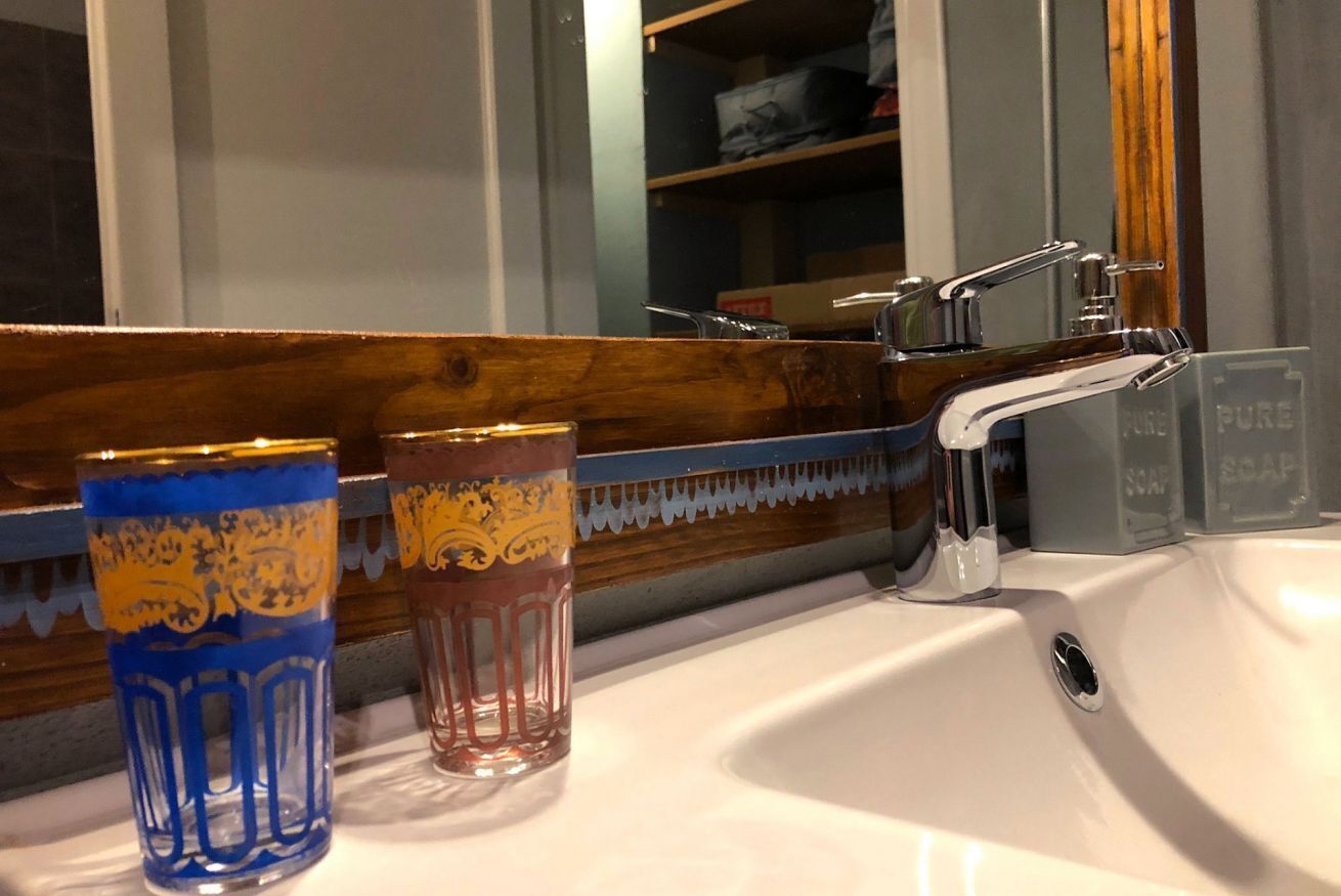 Un lavabo in bagno con due bicchieri decorativi, uno specchio e un rubinetto.