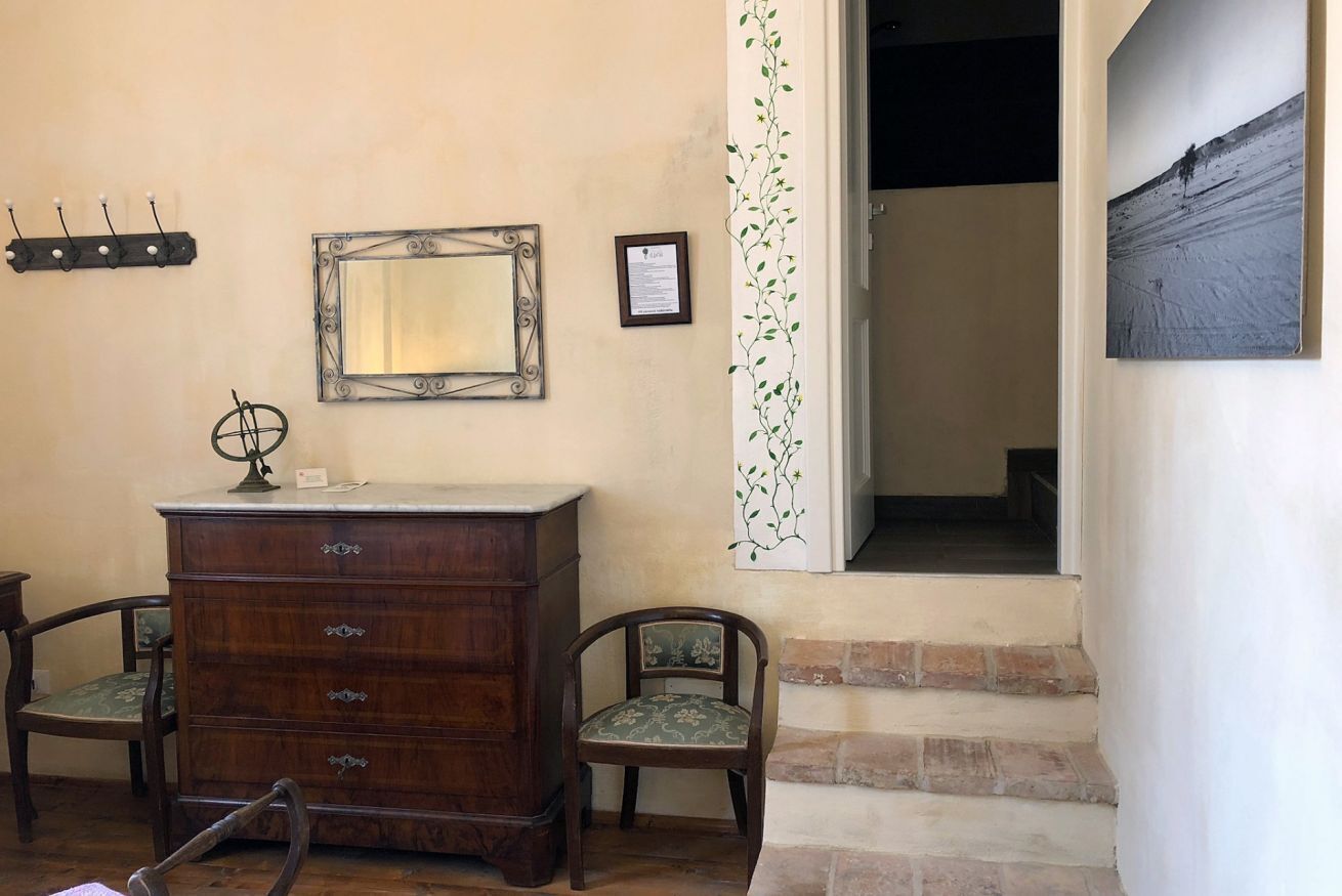 Une pièce comprenant une commode en bois, deux chaises, un miroir et un tableau encadré accroché au mur.