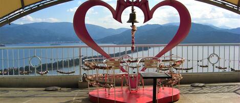 Un carrusel con una parte superior en forma de corazón, frente a un paisaje montañoso.