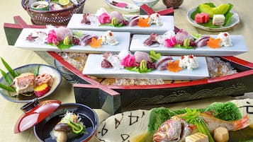 Variedad de platos de sushi sobre una mesa, incluyendo sashimi, nigiri y rollos, acompañados de recipientes pequeños con salsas y verduras encurtidas.