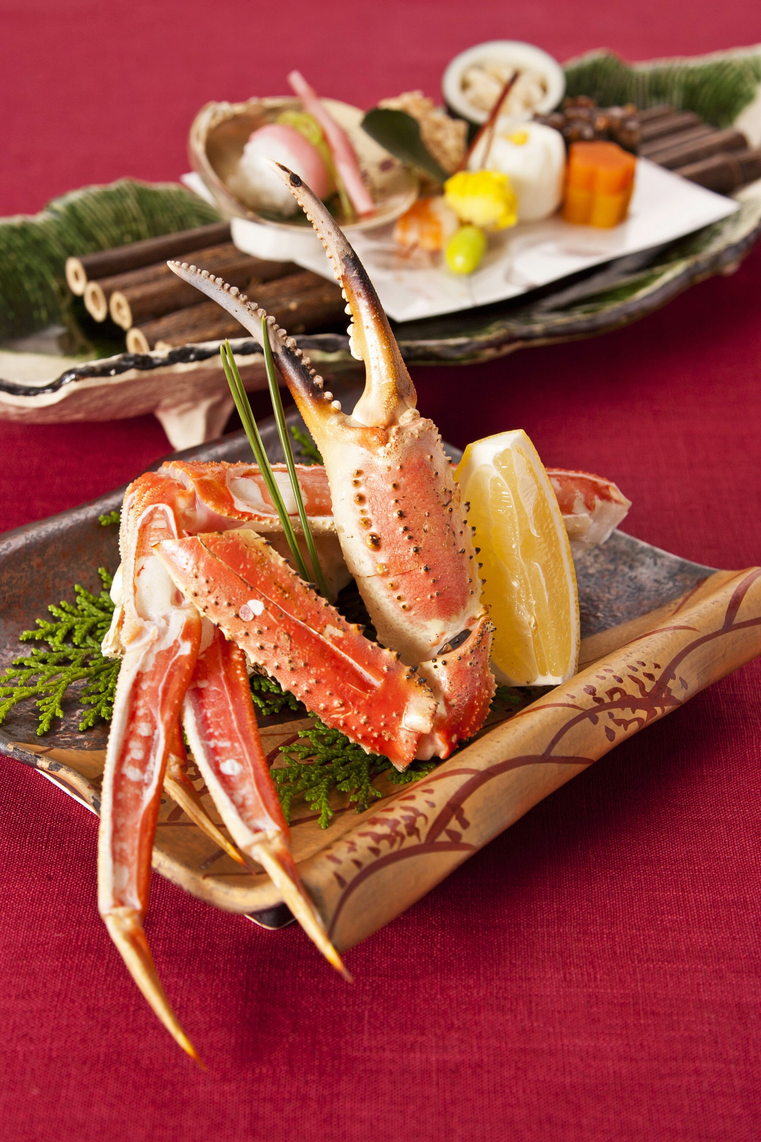 A seafood dish with crab legs and lemon on a wooden plate.