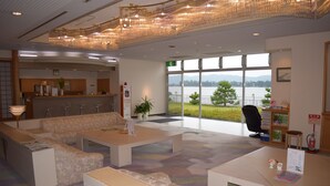A modern lobby with a reception desk, seating area, and large windows offering a view of a lake. - The Gran Resort Amanohashidate (Miyazu)