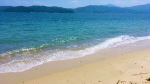A beach with clear blue water, sandy shore, and distant mountains. - The Gran Resort Amanohashidate (Miyazu)
