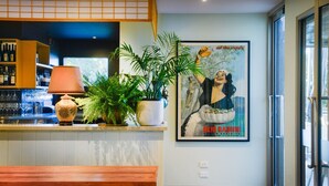Eine Bar mit einem Blumentopf, einer Lampe und einem gerahmten Poster an der Wand.