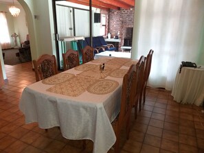 Un comedor con una mesa larga cubierta con un mantel estampado, rodeado de sillas de madera.