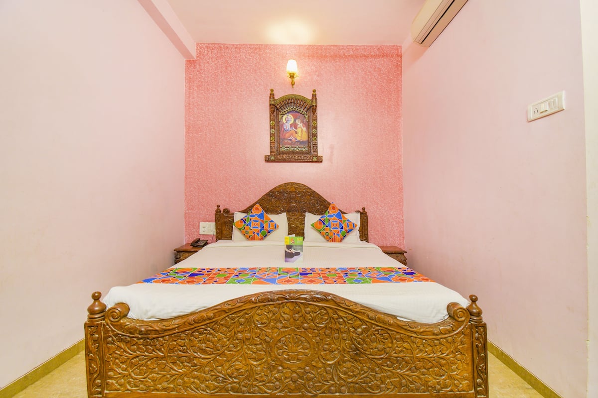 Ein Schlafzimmer mit einem hölzernen Bett, rosa Wänden und einer dekorativen Wandgestaltung.