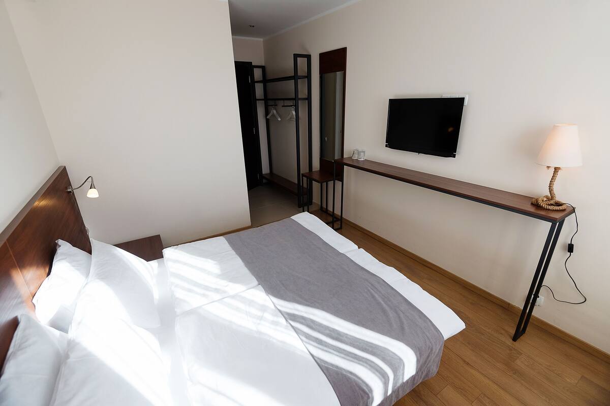 A hotel room with a bed, a desk, a TV, and a lamp.