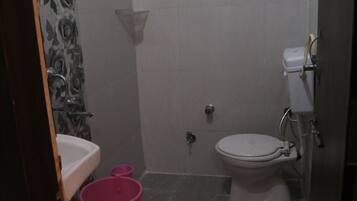 A small bathroom with a toilet, sink, and a shower area.