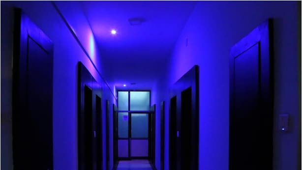 A hallway with doors on both sides, leading to a room with a window at the end. - Hotel Shri Karani Vilas (Chittorgarh)