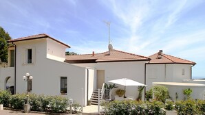 A two-story building with a tiled roof, a satellite dish, and a staircase leading to the upper floor.