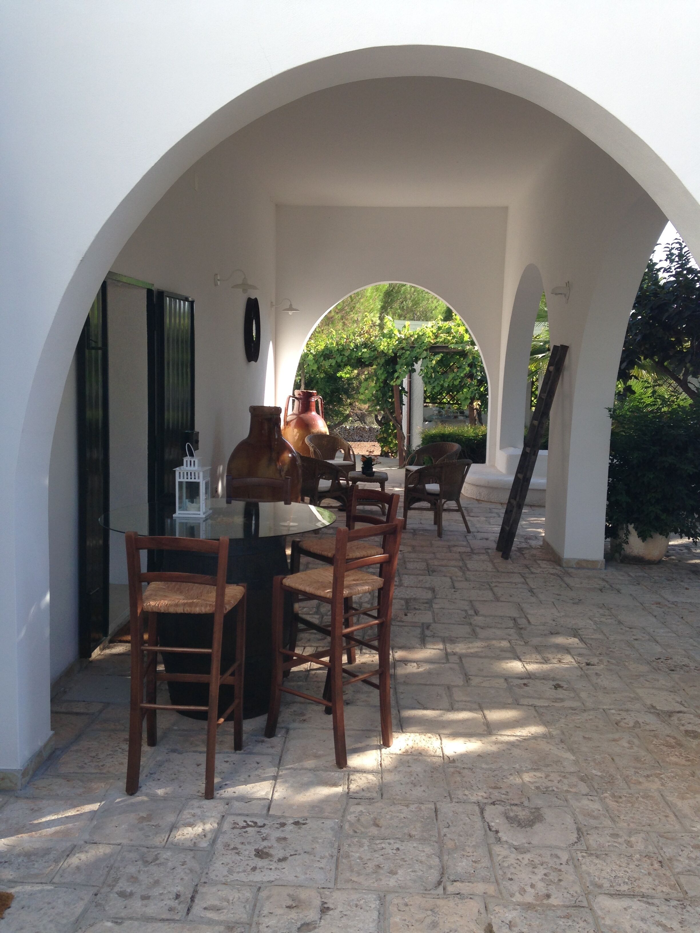 Un patio al aire libre con una mesa y sillas, rodeado de arcos blancos.