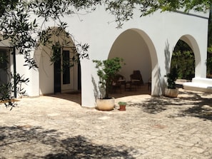 A courtyard with white walls, arches, and potted plants. - La Vecchia Tabaccheria B&B (Ostuni)