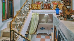 Una escalera con barandillas de metal decoradas que conduce a un dormitorio con una cama y una mesita.