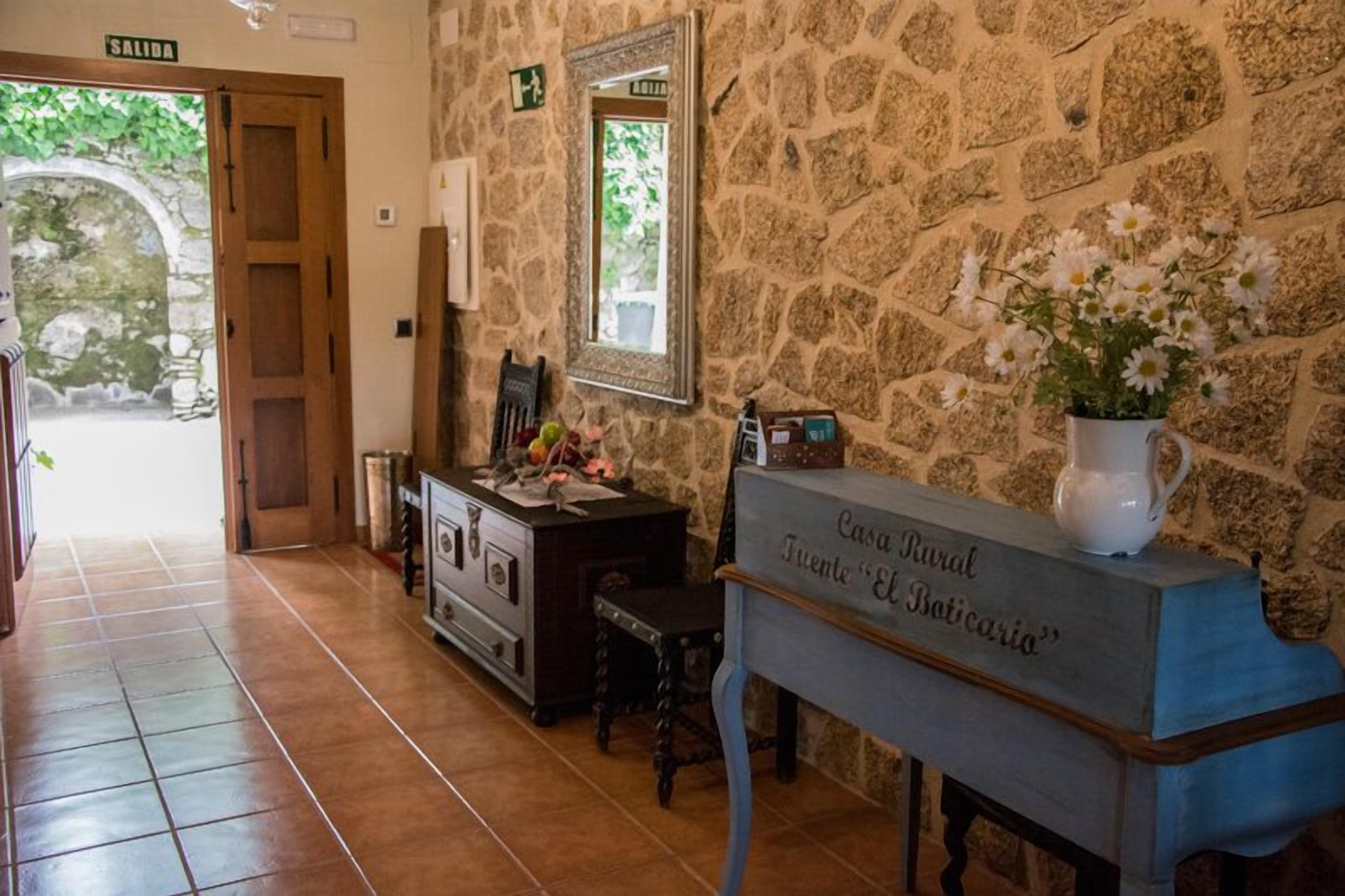 Eine Steinsäule, eine Holztür mit der Aufschrift „SALIDA“ und eine Klavierbank mit einem Schild, auf dem „Casa Rural Punta El Baticalo“ steht.