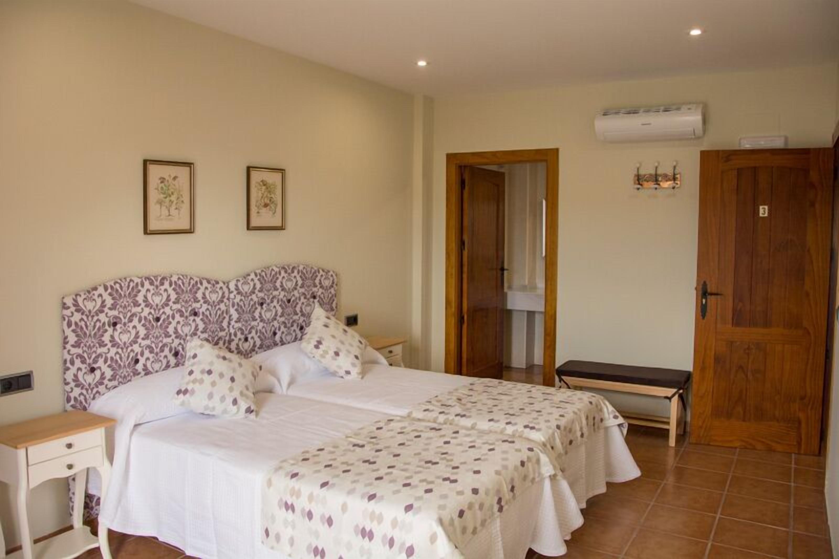 A bedroom with two beds, a wooden door, and an air conditioning unit.